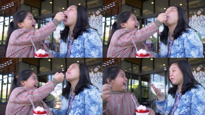 可爱的女孩用冰淇淋喂樱桃她妈妈在店外