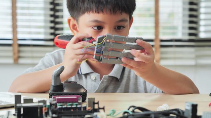 男孩在家里用电脑构建和编程，并将机器人手臂作为学校科学项目。他对自己的工作很满意。教育、儿童、技术、