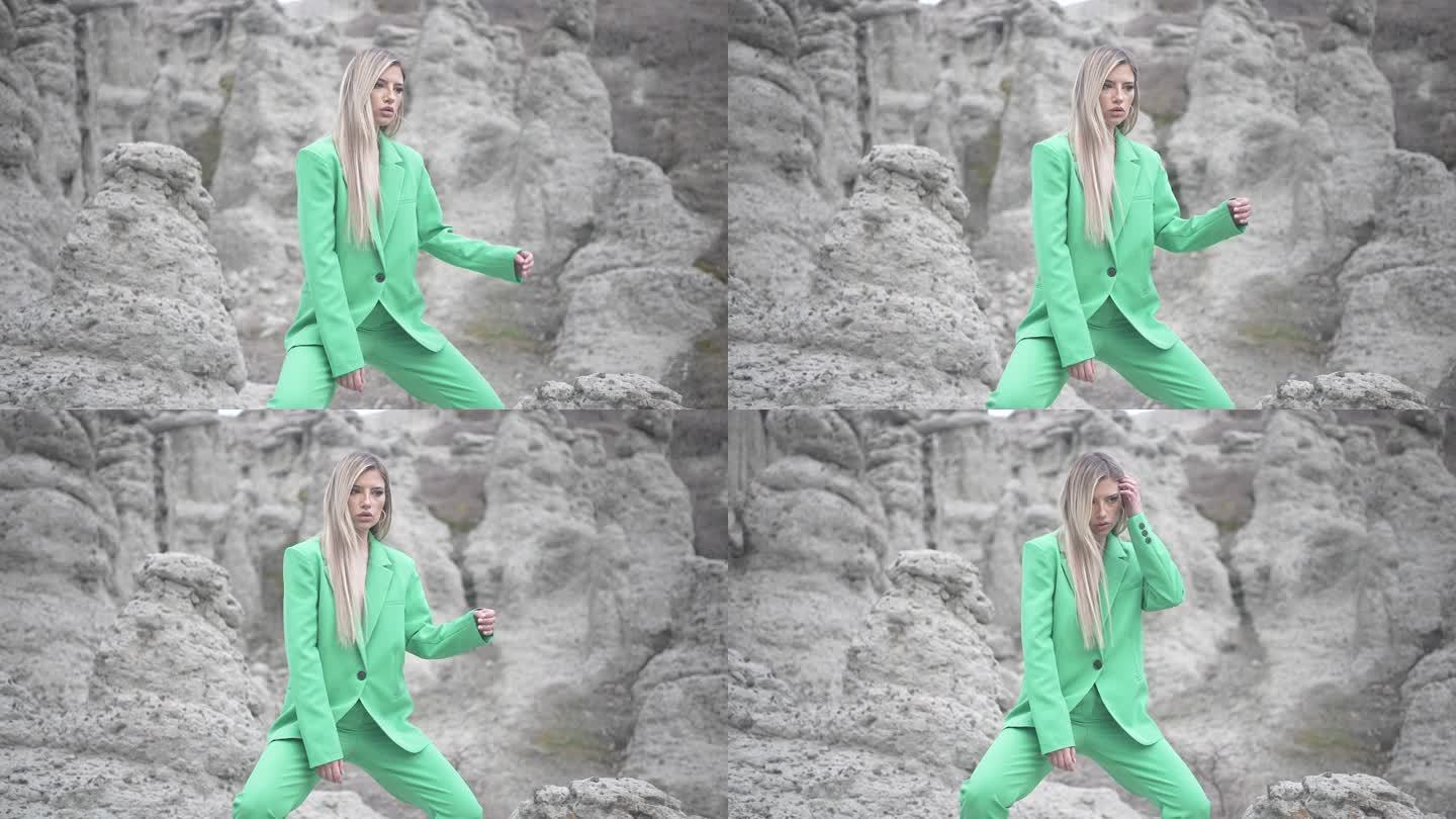 穿着绿色西装的优雅女性蹲在山上的仪式岩石前