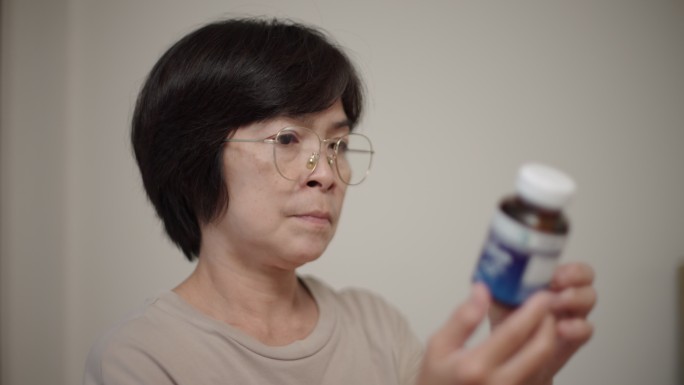 在家看药的女人戴眼镜的女性察看瓶身上的药