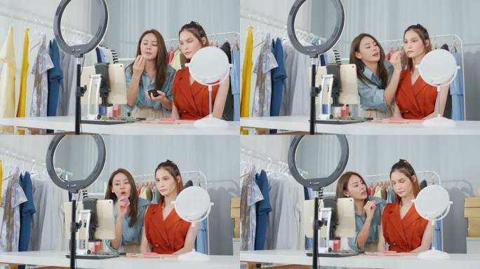 两位亚洲女性在家里对着摄像机聊天，回顾化妆品。美女博主影响力女性朋友在办公室商店的平板电脑上直播并向