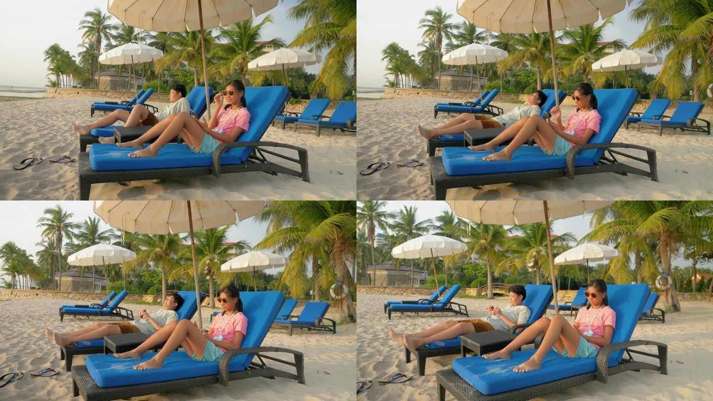 早上在酒店或度假村度假时，带着太阳镜的快乐亚洲孩子们一起在沙滩椅上放松，享受家庭、生活方式的概念。