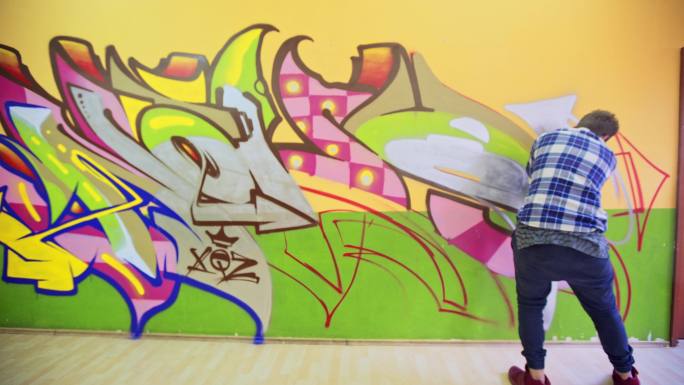 年轻艺术家在橙色墙上涂鸦