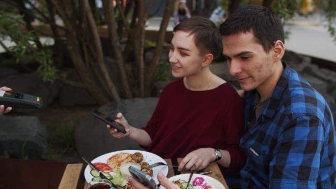 年轻夫妇在咖啡馆用智能手机付款