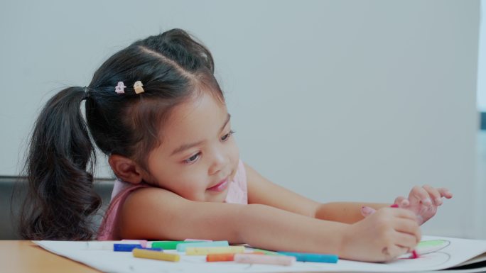 小女孩在画册上画画和着色。