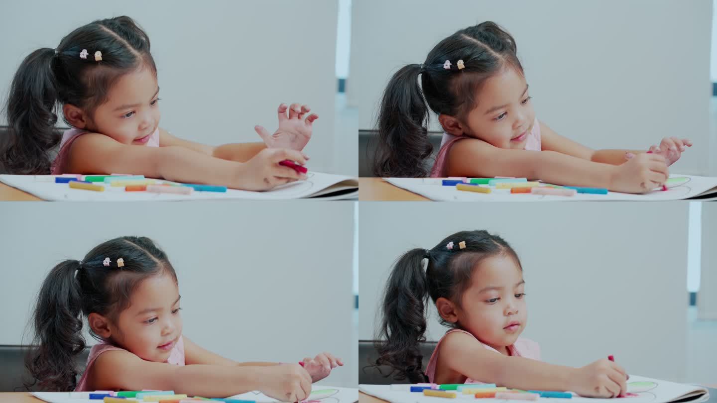 小女孩在画册上画画和着色。