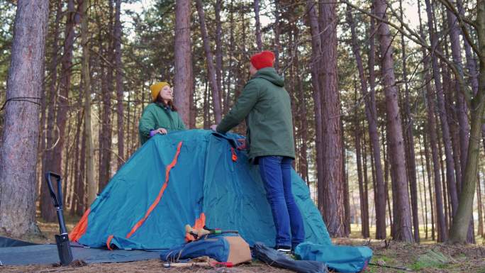 漂亮的时髦的异性恋情侣搭建帐篷露营