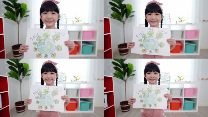 一个可爱的六岁亚洲女孩站在教室里，手里拿着她的彩色铅笔画，展示她以拯救世界为主题的信息，她画了一个覆