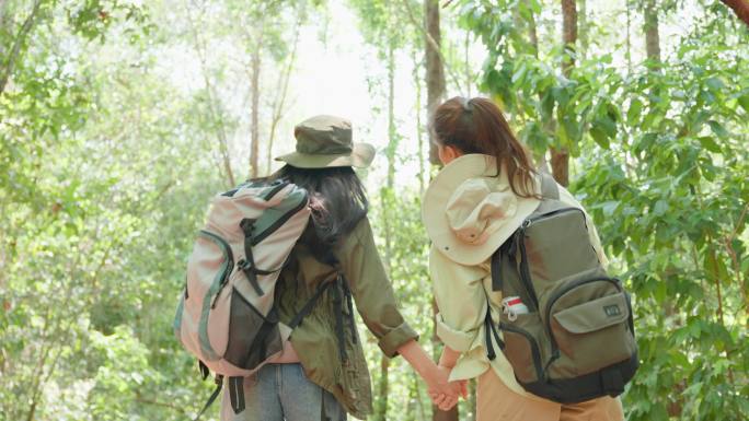 亚洲美女两位背包客一起在森林野外旅行。吸引人的年轻女性朋友在夏季度假旅行中快乐地散步和探索自然森林。