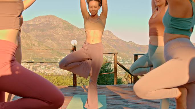年轻的瑜珈师在大自然中的一个精神健康疗养所，用一条腿的姿势练习平衡，感觉平静和平和。一群妇女在清晨的