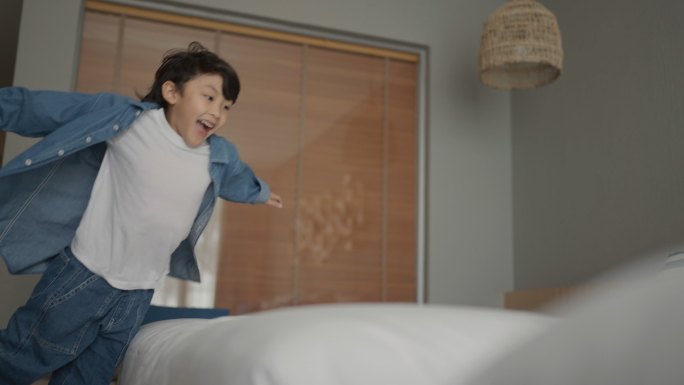 快乐的孩子在酒店房间的床上奔跑