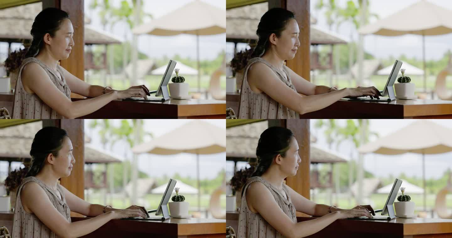 亚洲女商人在度假胜地休闲旅行时使用笔记本电脑做生意