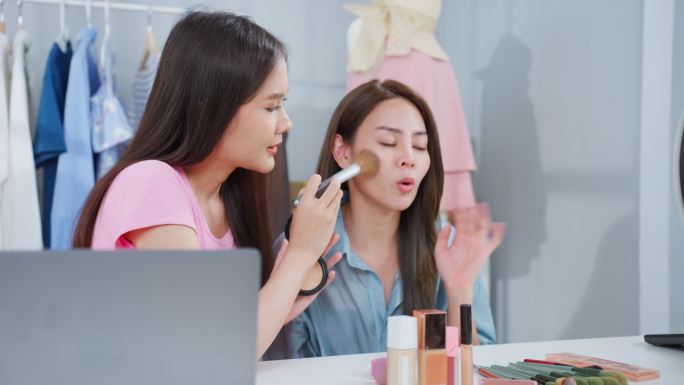 两位亚洲女性在家里对着摄像机聊天，回顾化妆品。美丽的美容博主Influencer女性朋友在办公室商店