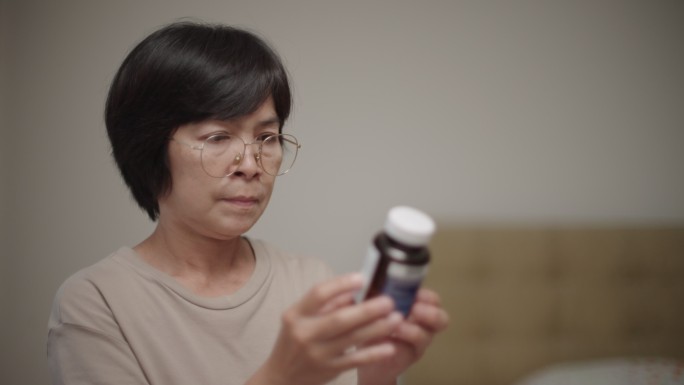 在家看药的女人戴眼镜的中年妇女看药品服用
