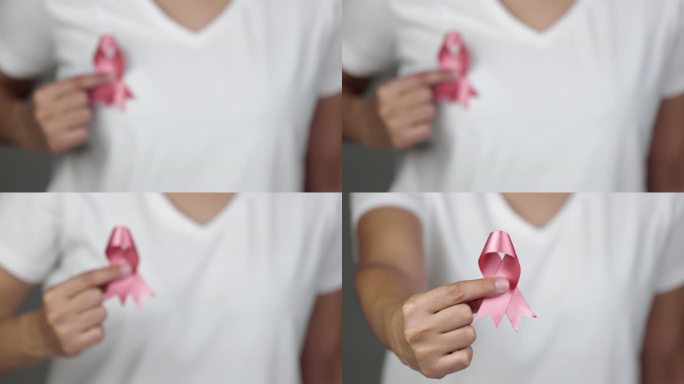 一名女子向镜头展示粉色乳腺癌意识丝带