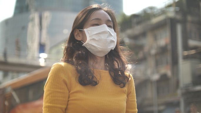 在城市街头户外戴口罩的亚洲女性