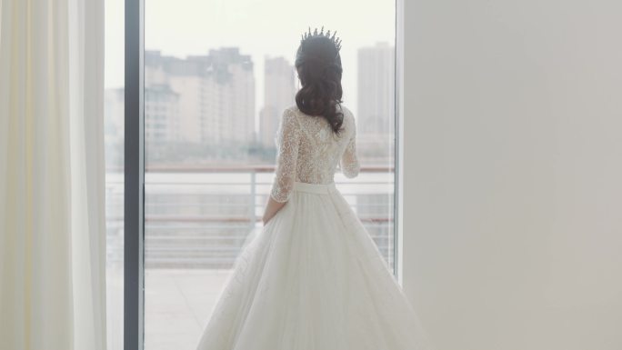 一位穿着婚纱的年轻女子站在落地窗前