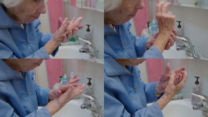 一位100岁的老人在浴室水槽上用手擦润肤乳液