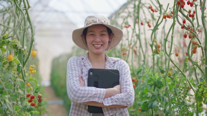 亚洲农民站在温室里自信地看着相机