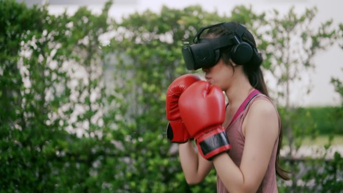 穿着VR耳机和运动服的年轻女孩正在拳击