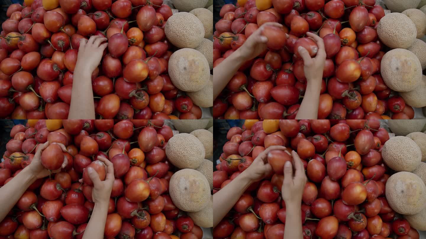 在农贸市场上，一名无法辨认的女子从零售摊位上抢番茄水果
