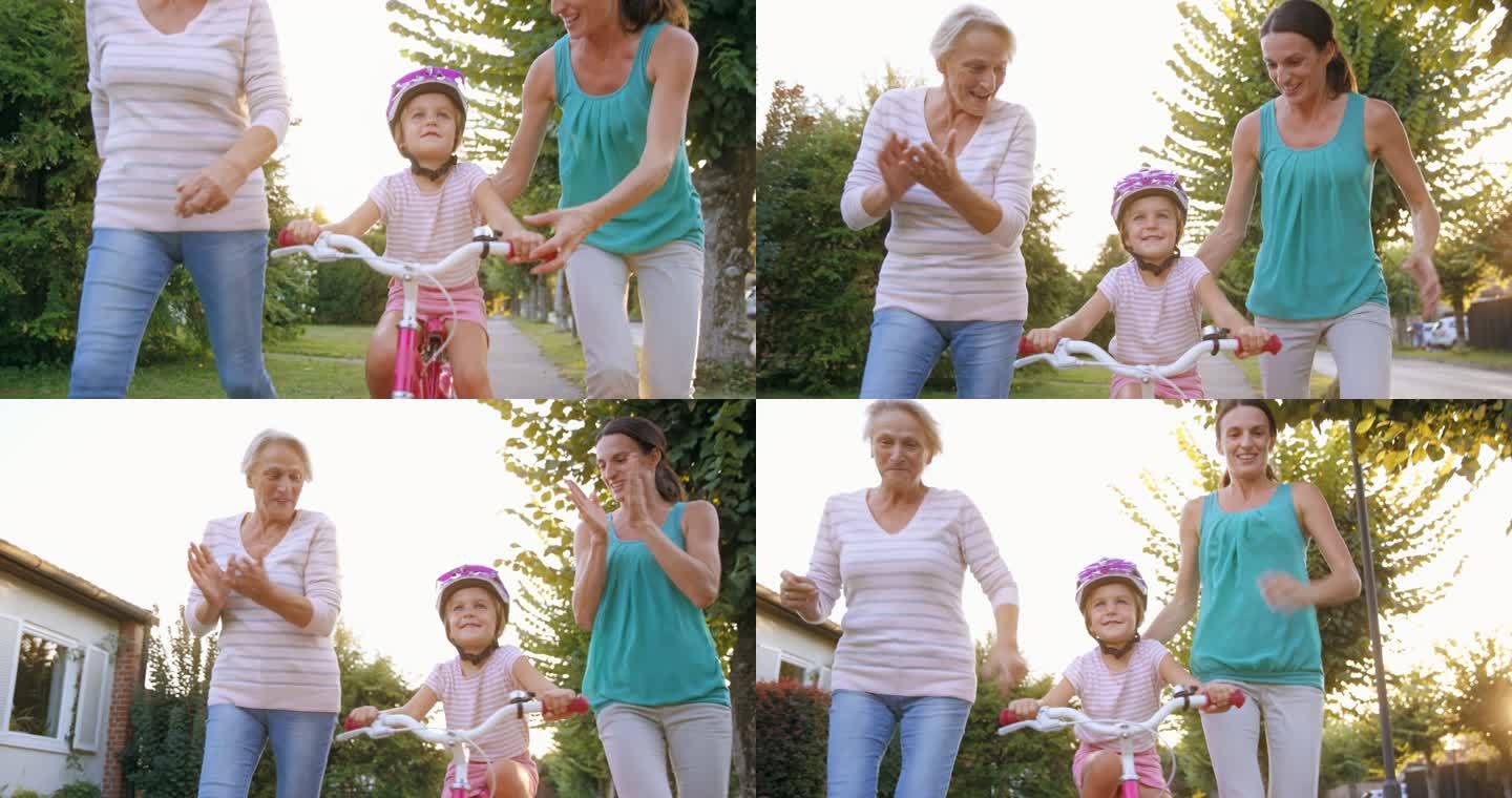 SLO MO妈妈放开了女儿的自行车，女孩第一次独自骑车，在奶奶的帮助下跑步并为她加油