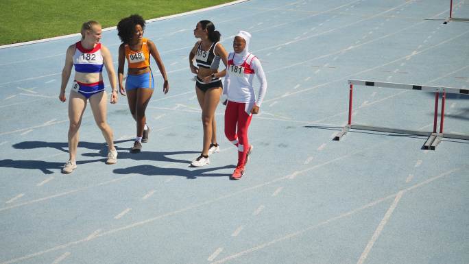 女子田径运动员在阳光充足的跑道上跨栏行走