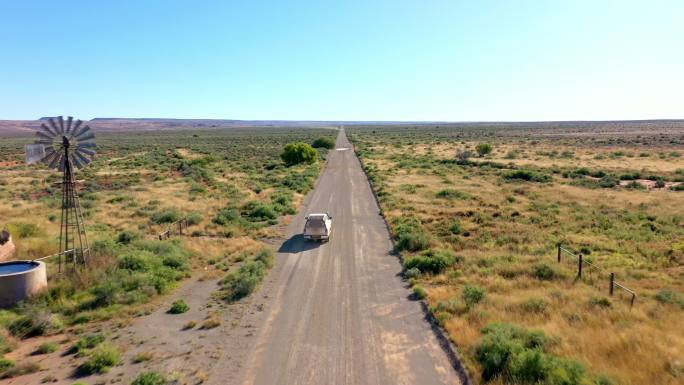 一辆汽车在空旷的公路上行驶，穿过广阔的沙漠平原地区。一辆在阳光明媚的山区快速行驶的汽车。一辆孤零零的
