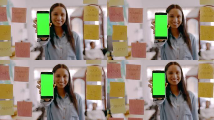 4k视频片段，一位年轻的女商人拿着绿色屏幕的手机，在办公室的玻璃墙上头脑风暴