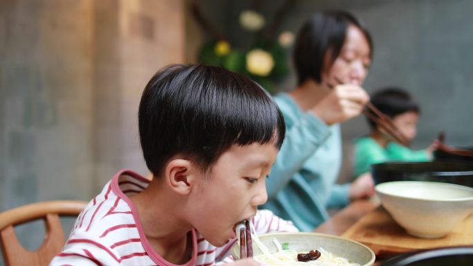 男孩用筷子吃米粉夹菜家长餐馆