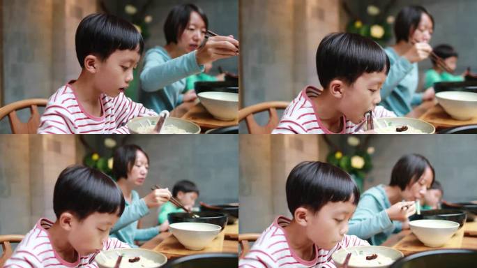 男孩用筷子吃米粉夹菜家长餐馆