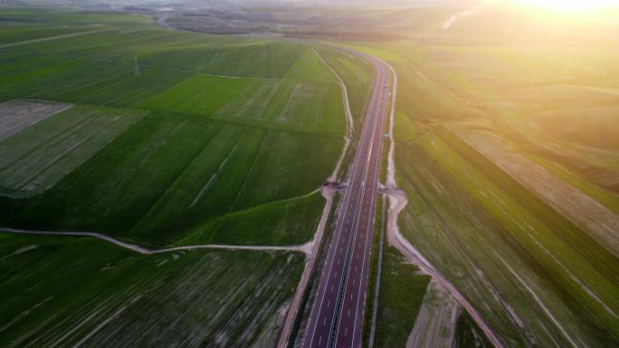 夕阳下航拍穿过麦田的高速公路