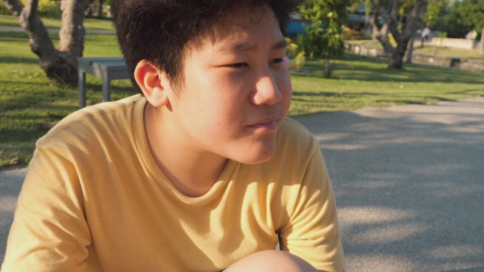 一名亚洲男孩在户外滑板运动中摔倒后膝盖擦伤。