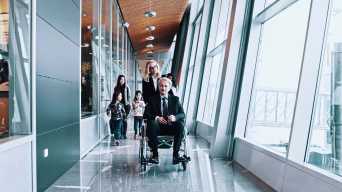 一群乘客，包括一名坐轮椅的老人，经过机场走廊