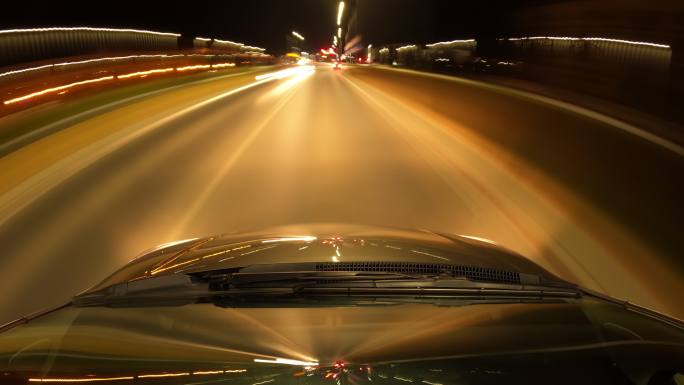 夜间驾车快速行驶。汽车行驶。时间流逝。汽车引擎盖和挡风玻璃上城市的反射光。