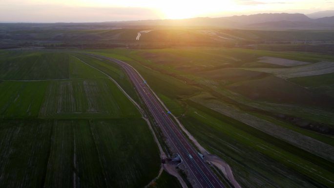 夕阳下航拍穿过麦田的高速公路