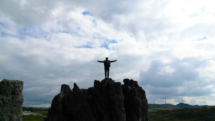 旅行徒步男人登上山顶张开双臂拥抱太阳天空