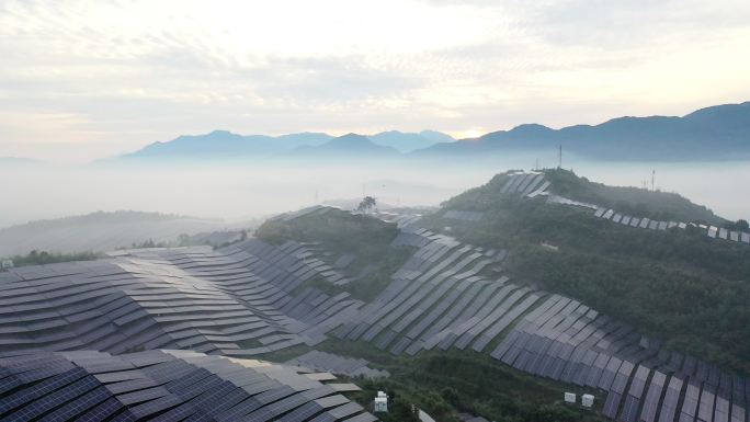晨雾中山坡上起伏的太阳能发电厂鸟瞰图