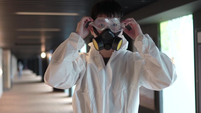 亚裔华人电影院卫生工作者戴着口罩准备在电影院走廊消毒