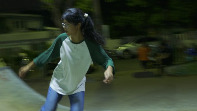 亚洲女孩在迷你坡道上玩极限运动滑冰的电影镜头。