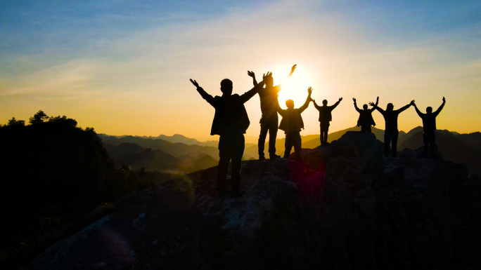一群人山顶欢呼举手拥抱太阳眺望远方成功者