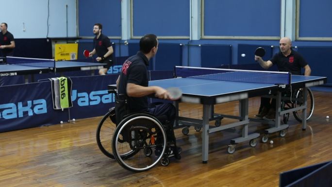 两个坐轮椅的男子打乒乓球