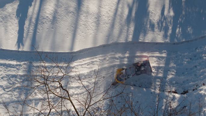 冬季降雪后，一名成年男子用吹雪机清理车道上的积雪。无人机慢动作视频正上方的鸟瞰图。
