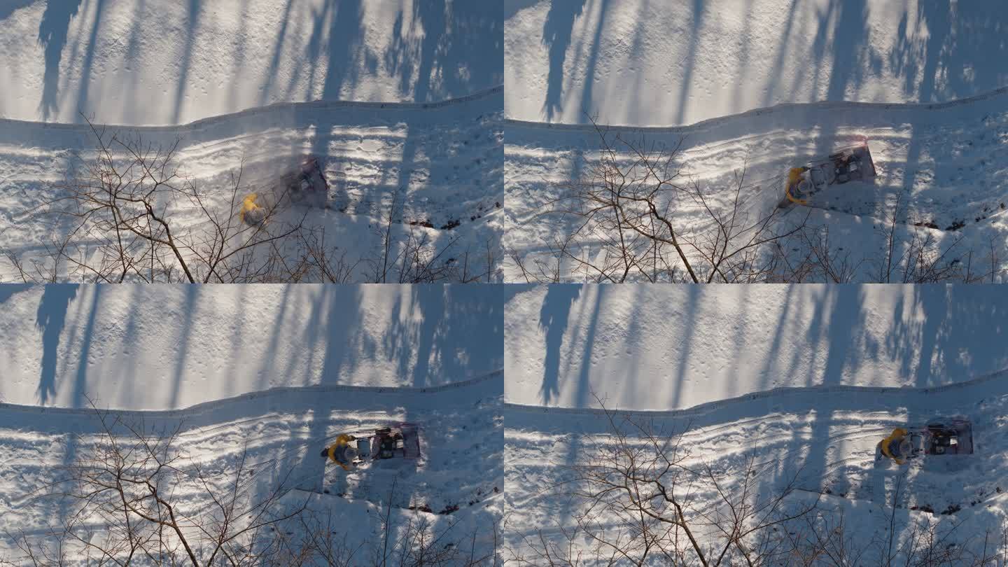 冬季降雪后，一名成年男子用吹雪机清理车道上的积雪。无人机慢动作视频正上方的鸟瞰图。