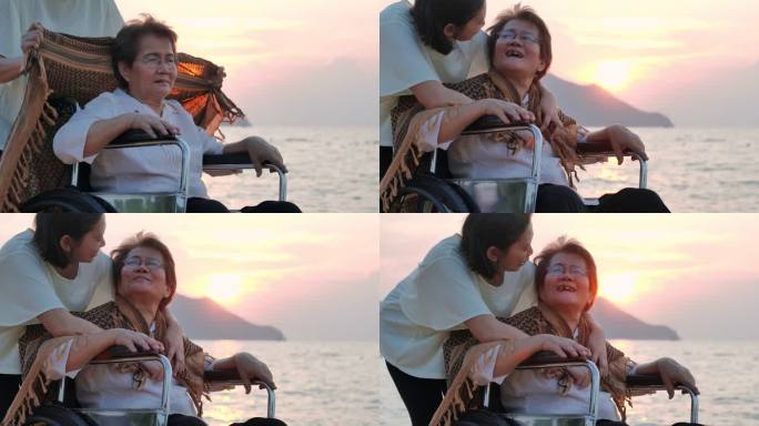 这张照片是一位面带微笑、快乐的亚洲资深母亲和她的成年女儿在沙滩上用毯子拥抱的照片。老年假期、假期、护