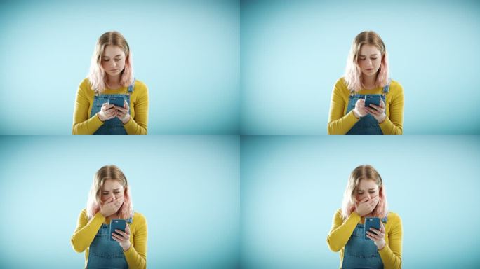 一位女士在蓝色工作室背景下厌恶地看着她的智能手机。一名年轻女性正在使用智能手机，收到坏消息后看起来很