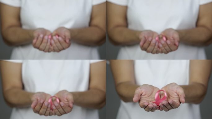 一名女子向镜头展示粉色乳腺癌意识丝带