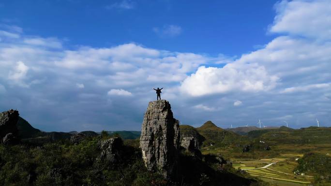 背包客登山在山顶张开双臂拥抱太阳眺望远方