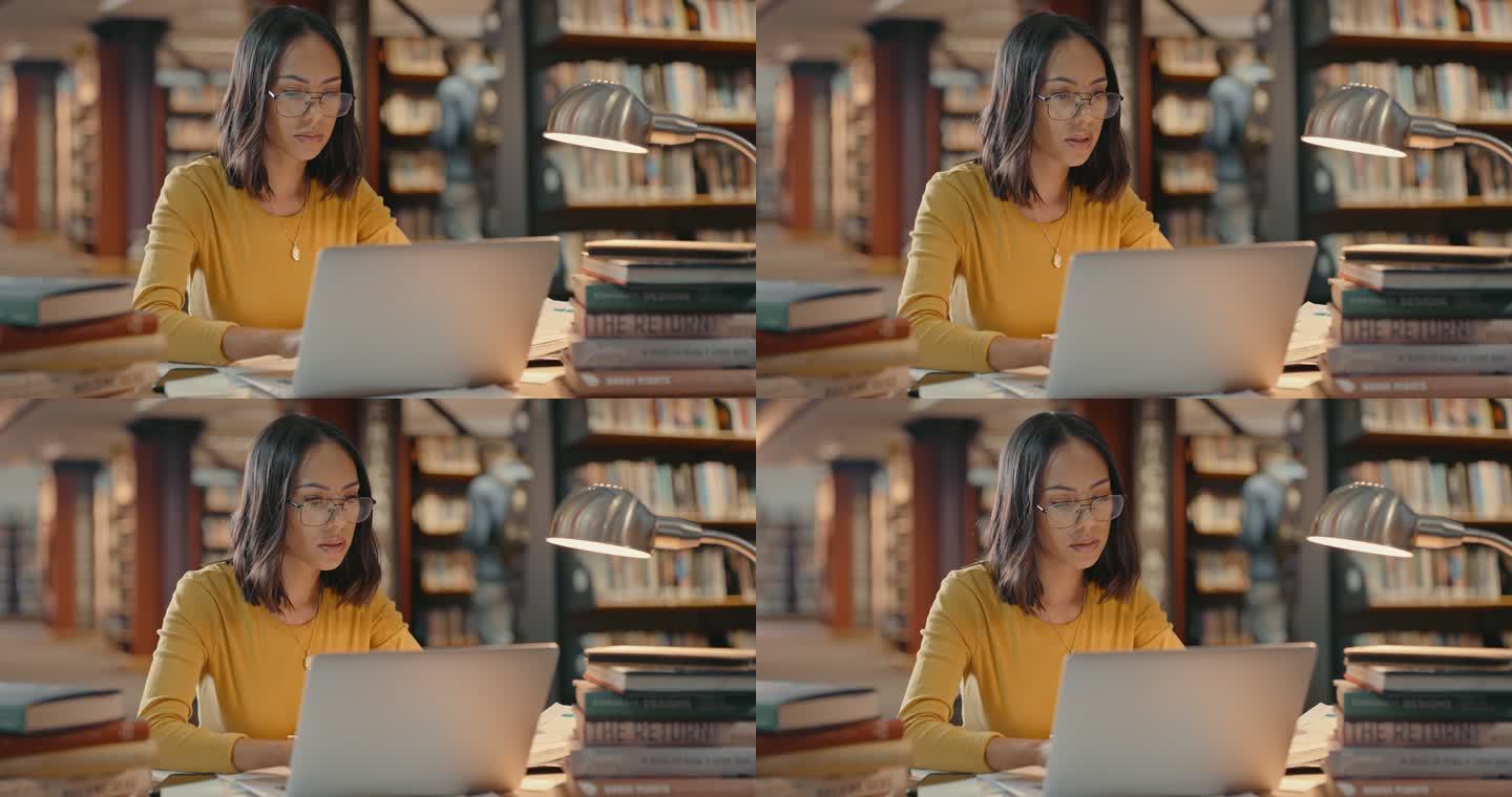 戴眼镜的年轻女学生使用大学图书馆的wifi在笔记本电脑上进行在线研究，以完成课堂作业或准备期末考试。