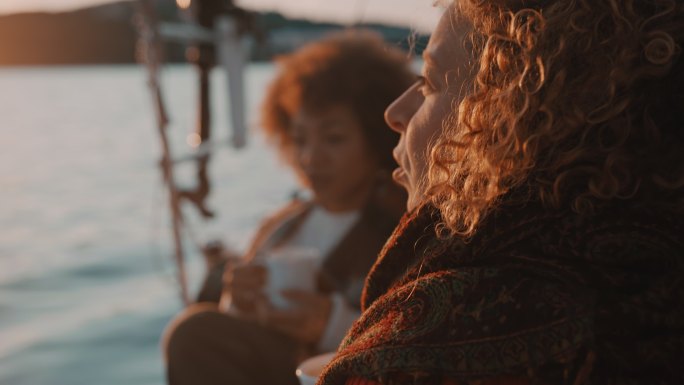 黄昏时分，两名女子在帆船甲板上喝咖啡